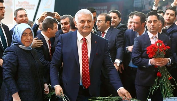 Binali Yildirim, flanked by wife Semiha Yildirim, holds red carnations as he arrives for the second extraordinary congress of the AK Party at the Ankara Arena on Sunday.