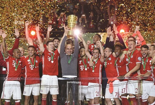 Bayern Munichu2019s Spanish head coach Pep Guardiola celebrates with the German Cup.