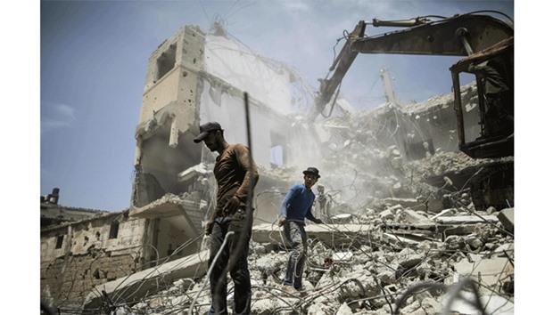 Palestinian men work on the remains of a building destroyed during the 50-day Israeli offensive in Gaza City in 2014. Reconstruction aid to over 1,000 families in Gaza has been suspended due to a lack of materials.