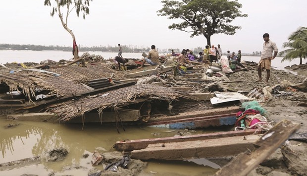 Villagers gathering around the wreckage of destroyed homes in Chittagong yesterday, after Cyclone Roanu struck the southern coastline.