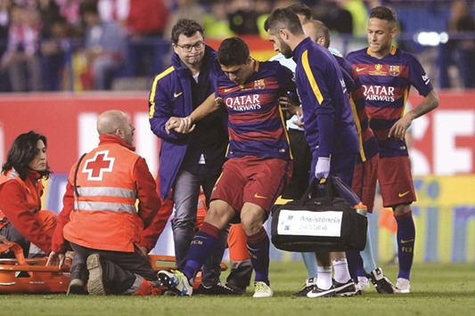 Luis Suarez (centre) is assisted after being injured during Barcelonau2019s Spanish Copa del Rey final against Sevilla FC at the Vicente Calderon stadium in Madrid on Sunday. (AFP)