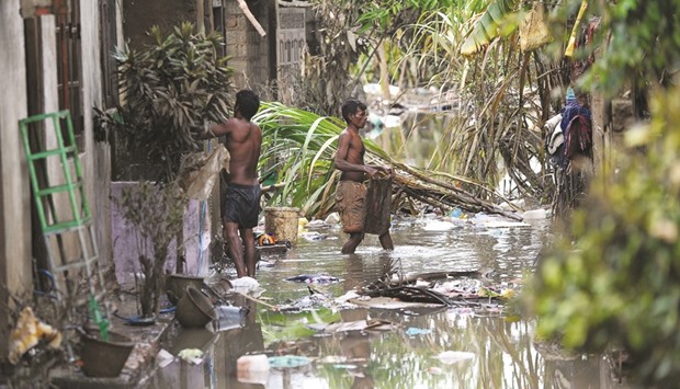 Residents clearing debris from outside homes following flooding in the Kolonnawa suburb of Colombo yesterday.