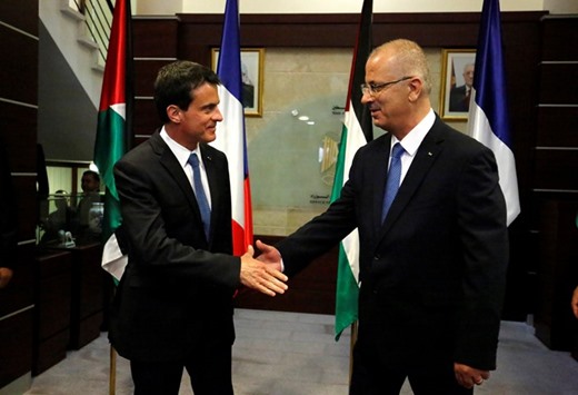 Palestinian Prime Minister Rami Hamdallah (right) shakes hands with French Prime Minister Manuel Valls before their meeting in the West Bank city of Ramallah yesterday.