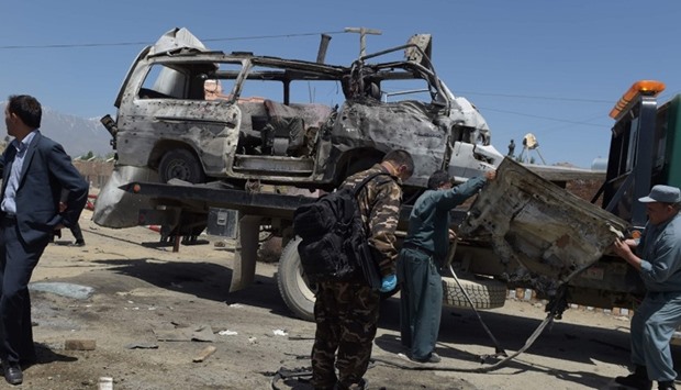 Afghan security personnel stand near damaged vehicles at the scene of a suicide bomb attack