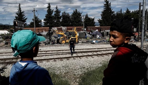 Migrant boys look on as a bulldozer removes tents from the train tracks during a police operation at a migrant camp at the border between Greece and Macedonia, near the village of Idomeni on Wednesday.