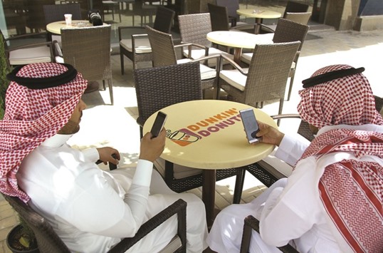 Saudi men explore social media on their mobile devices as they sit at a cafe in Riyadh.