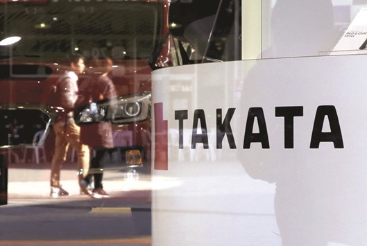A logo of Takata Corp is seen with its display as people are reflected on a window at a showroom for vehicles in Tokyo. Facing the consequences of the largest-ever US safety recall after its airbag inflators malfunctioned, the firm named an outside committee in February to lead an overhaul.