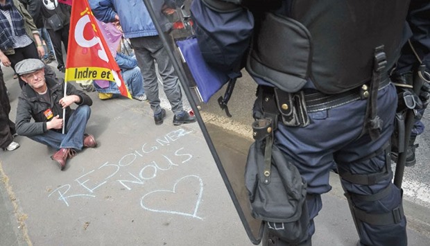 A protester holding a CGT union flag faces riot police during a demonstration yesterday against the governmentu2019s planned labour law reforms, in Tours, central France. The writing reads u2018join usu2019.
