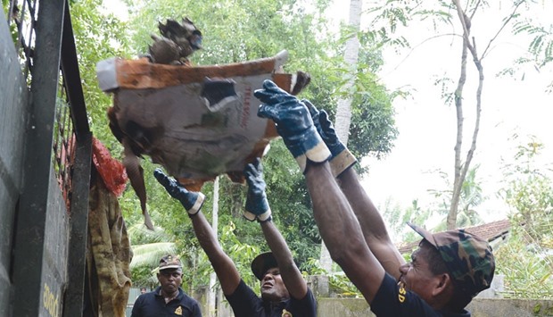 Sri Lankan Civil Security Department personnel clean up a street hit by floods in the Colombo suburb of Kaduwela yesterday.