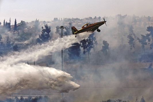 A water bomber works to put out a fire in the woods around Jerusalem yesterday morning.
