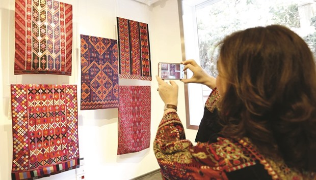 A woman takes a picture of textiles during an exhibit of Palestinian embroidery in the Lebanese capital Beirut.