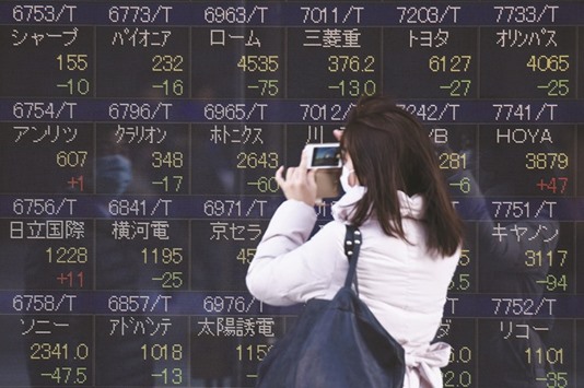 A woman uses her smartphone to take pictures of share prices at an electronic quotation board in Tokyo. The Nikkei 225 closed up 0.4% to 16,834.84 points yesterday.