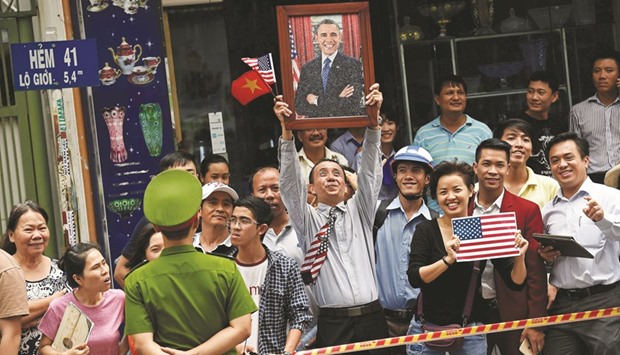 A man holding up a portrait of  President Barack Obama as people lined up the streets to catch a glimpse of the US leader on his way to the airport at the end of a two-day visit to Ho Chi Minh City on Wednesday.
