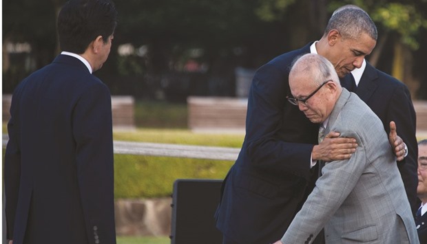 Abe watches as Obama hugs a survivor of the 1945 atomic bombing of Hiroshima, during a visit to the Hiroshima Peace Memorial Park yesterday.