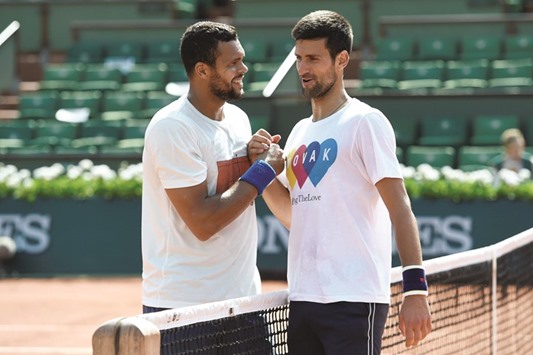 Franceu2019s Jo-Wilfried Tsonga (left) shakes hands with Serbiau2019s Novak Djokovic after their training session in Paris on Saturday. Tsonga retired from his third round match against Ernests Gulbis. (AFP)