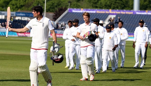 England's captain Alastair Cook (L) leaves the field after his team won the 2nd Test match on the fourth day of the second test cricket match between England and Sri Lanka at the Riverside in Chester-le-Street, north east England