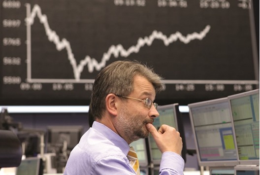A financial trader monitors his computer screens beneath a display of the DAX Index curve at the Frankfurt Stock Exchange. After starting the year with bullish calls, strategists and analysts have become increasingly sceptical about European equities, projecting flat annual returns in the Stoxx 600 and a decline in corporate profits.