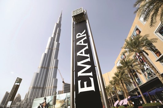 An Emaar Properties sign stands beside billboards promoting the Opera district developments near the Burj Khalifa tower in Dubai (file). Dubaiu2019s index fell 1.6% yesterday, ending five session of gains as investors lacked impetus to build further positions. Emaar lost 2.2%.