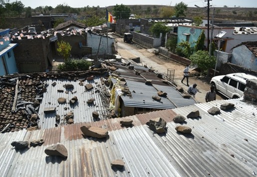 Villagers walk past houses struck by debris following a fire at an ammunition depot in Pulgaon some 100km from Nagpur yesterday.