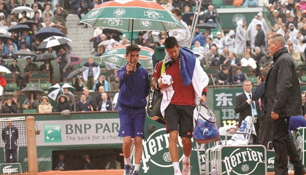Serbiau2019s Novak Djokovic leaves the court as it rains during his French Open match against Spainu2019s Roberto Bautista Agut at Roland Garros in Paris yesterday. (Reuters)
