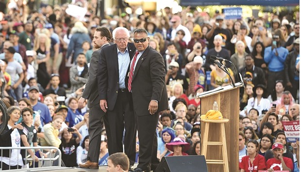 Secret Service agents protect Democratic presidential candidate Bernie Sanders on stage after some people climbed over a barricade and approached him during his speech at Frank Ogawa Plaza in Oakland on Monday.