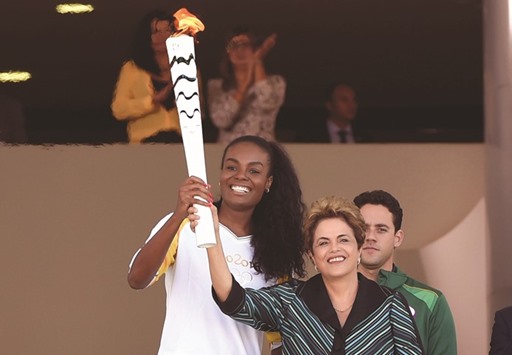 Brazilian volleyball player Fabiana Claudino (L) and Brazilian President Dilma Rousseff hold the Olympic torch at Planalto Palace in Brasilia following the flameu2019s arrival in the country yesterday ahead of the Rio 2016 Olympic Games in August. (AFP)