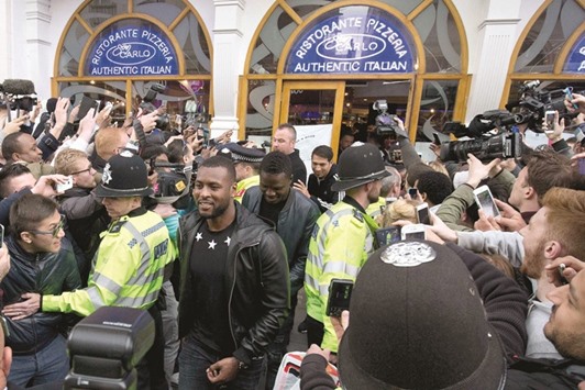 Leicester Cityu2019s captain Wes Morgan (C) is mobbed by fans as he leaves an Italian restaurant after having lunch with teammates.
