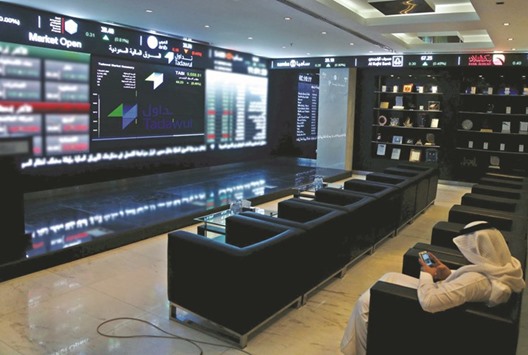 A trader uses his mobile as he monitors screens displaying stock information at the Saudi Stock Exchange in Riyadh (file). The Saudi index fell 1.2% yesterday as petrochemical blue chip Saudi Basic Industries lost 2.4%.