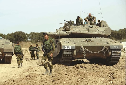 Israeli soldiers stand guard with their tank along the border between Israel and the Gaza Strip near the southern Israeli Kibbutz of Nahal Oz yesterday.