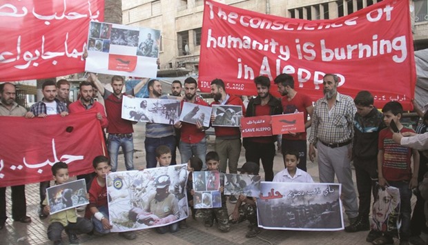 Syrians hold pictures and banners during a demonstration in solidarity with the civilians of the northern city of Aleppo yesterday in Idlib, in northwestern Syria.  Fierce fighting raged in the war-ravaged Aleppo and air strikes pounded rebels east of the capital Damascus as diplomats scrambled to salvage a collapsing truce.