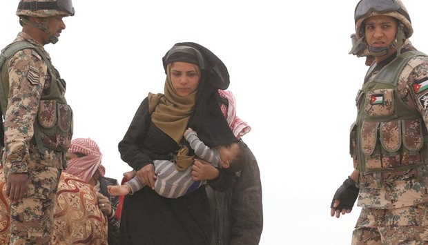 A Syrian woman holding a baby waits to cross to the Jordanian side of the Hadalat border after arriving from Syria yesterday. According to  Jordanian officials, around 5,000 people fleeing from recent attacks on the northern Syrian city of Aleppo are trying to cross into Jordan in search of safety.