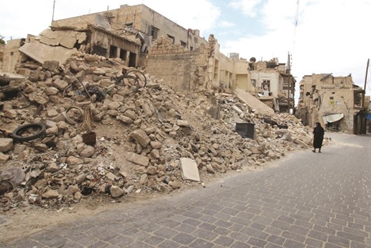 A woman walks yesterday near the rubble of collapsed buildings in the rebel-held area of Old Aleppo.