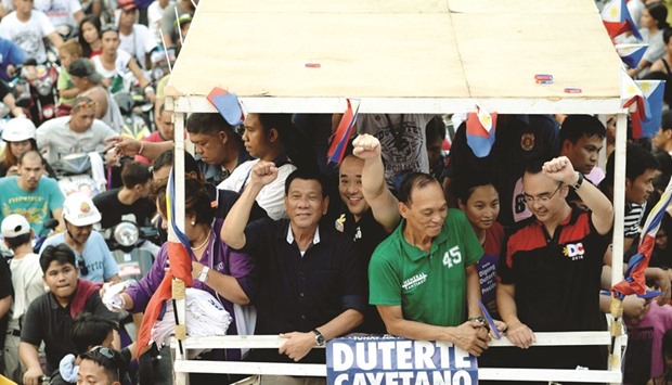A recent photo shows presidential candidate Rodrigo Duterte (left) gesturing to the crowd during a campaign motorcade near a port area in Manila.