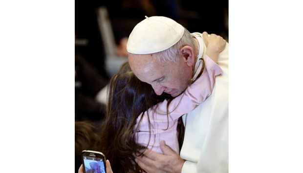 A girl hugs Pope Francis as he arrives at the Aula Paul VI for an audience with members of the non-governmental organisation Doctors with Africa at the Vatican yesterday.