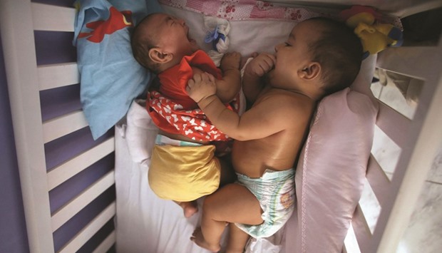 Five-month-old twins Laura (left) and Lucas lie in their bed at their house in Santos, Sao Paulo state.