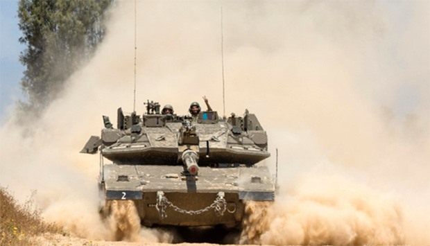 An Israeli tank rolls along the border near Gaza