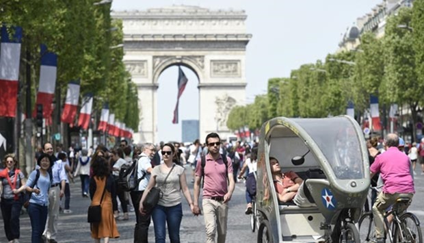 People walk past a man sleeping in his cycle-rickshaw on the Champs-Elysees in Paris on Sunday, as the French capital's most famous avenue went car-free for a day.