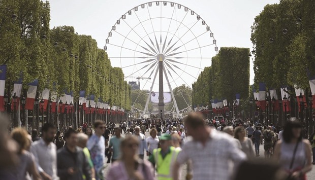 People walk along the French capitalu2019s Avenue des Champs-Elysees as the area goes car-free for a day, in the first instalment of a monthly effort to tackle pollution in Paris.