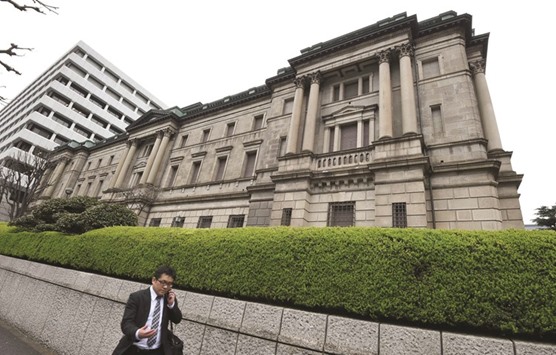 A businessman walks past the headquarters of the Bank of Japan in Tokyo. The BoJu2019s  bond buying has nearly trebled the monetary base in just over three years to more than $3.6tn as of April, according to a report.