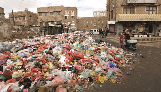 A girl pushes a wheel cart with water jerrycans past a pile of rubbish bags on a street during a strike by garbage collectors demanding delayed salaries in Sanaa, yesterday.