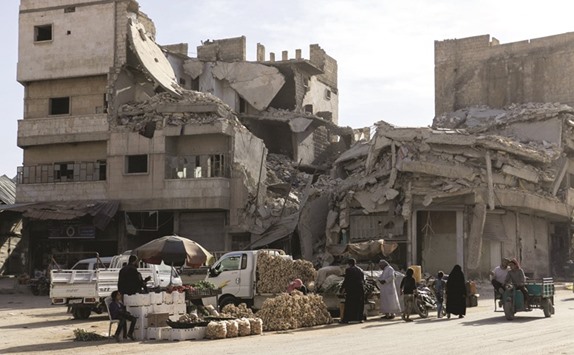 Sellers showcase their produce near destroyed buildings in the Syrian city of Al-Bab in the northern Aleppo province at sunset yesterday.