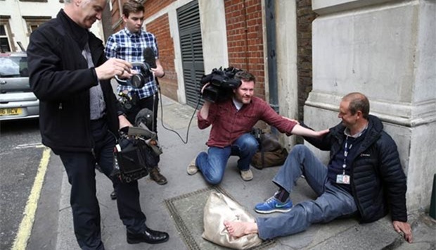 Giles Wooltorton, a cameraman who works for the BBC, sits on the ground after his foot was injured as a car carrying Britain's opposition leader Jeremy Corbyn was driven into a building in central London on Thursday.