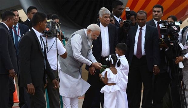 Prime Minister Narendra Modi is watched by Sri Lankan Prime Minister Ranil Wickremesinghe as he receives betel leaves from two Sri Lankan children after arriving at Bandaranaike International Airport in Colombo on Thursday.