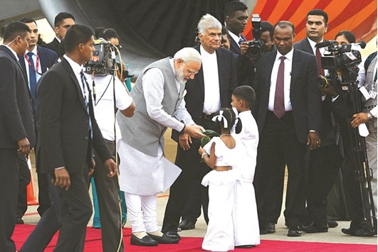 Sri Lankan Prime Minister Ranil Wickremesinghe looks on as Indiau2019s Prime Minister Narendra Modi receives betel leaves from two Sri Lankan children after arriving at Bandaranaike International Airport in Colombo yesterday.
