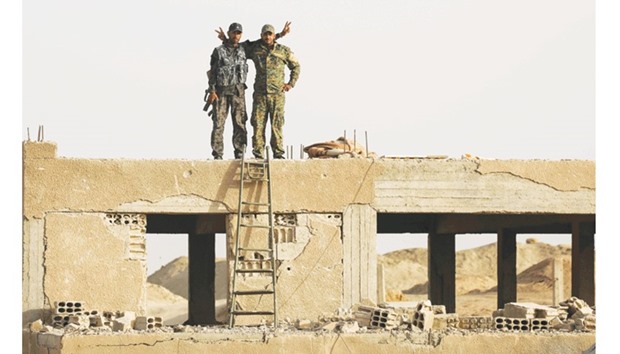 Members of the Kurdish Peopleu2019s Protection Units (YPG) flash victory signs as they stand on a building in the town of Al Karamah, 26km from the Islamic State bastion of Raqa.