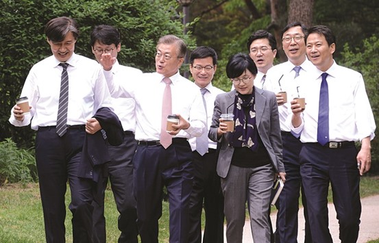 South Korean President Moon Jae-in talks with senior secretaries as they walk outside the Presidential Blue House in Seoul.