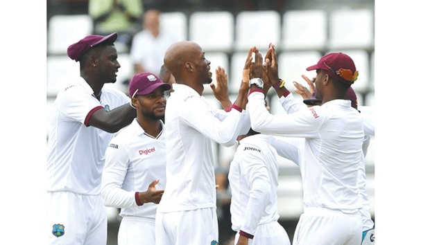West Indies bowler Roston Chase (centre) celebrates with teammates after taking a Pakistan wicket during the third and final Test at the Windsor Park Stadium in Roseau, Dominica. (AFP)