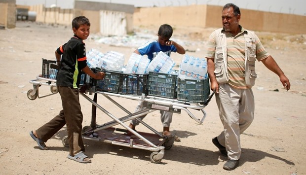 Volunteers carry water for the displaced as Iraqi forces battle with Islamic State militants