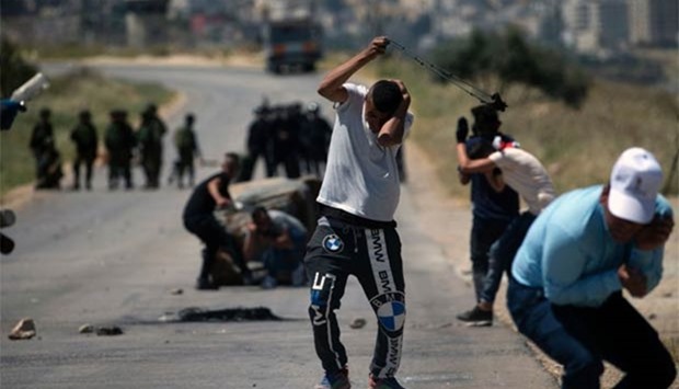 A Palestinian protester uses a slingshot to hurl stones towards Israeli security forces during clashes in the West Bank village of Beit Furik, east of Nablus on Friday.