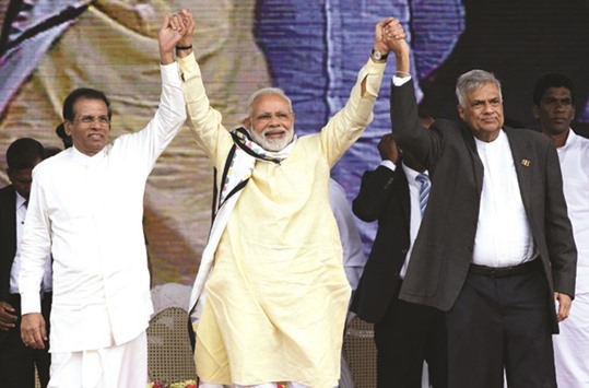 Indiau2019s Prime Minister Narendra Modi, centre, joins hands with Sri Lankan President Maithripala Sirisena, left, and Prime Minister Ranil Wickremesinghe after addressing a public rally in the tea-growing town of Norwood, some 80km east of Colombo, yesterday.